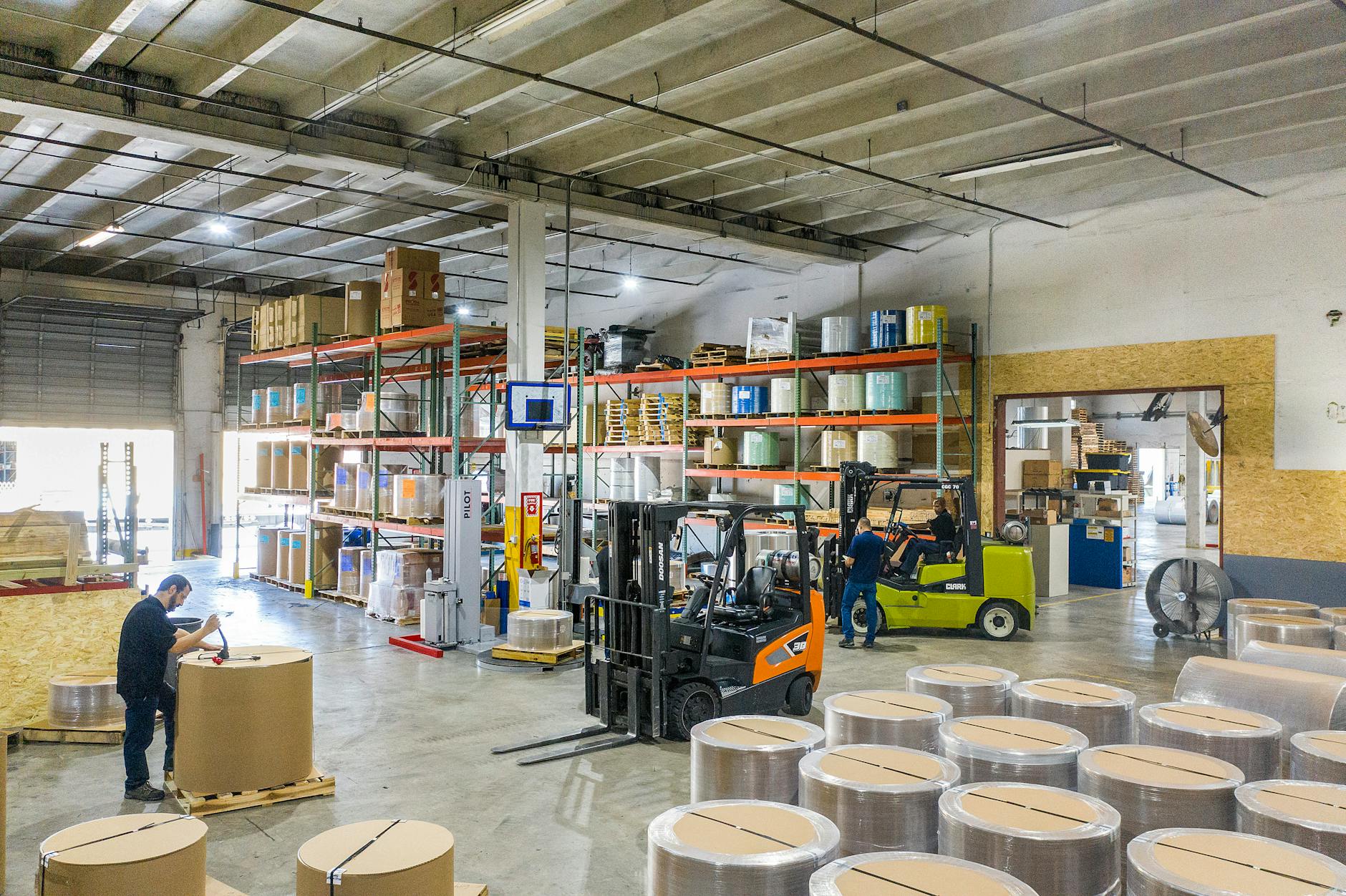 Industrial warehouse storing large rolls of paper material, representing paper reel inventory for bag manufacturing