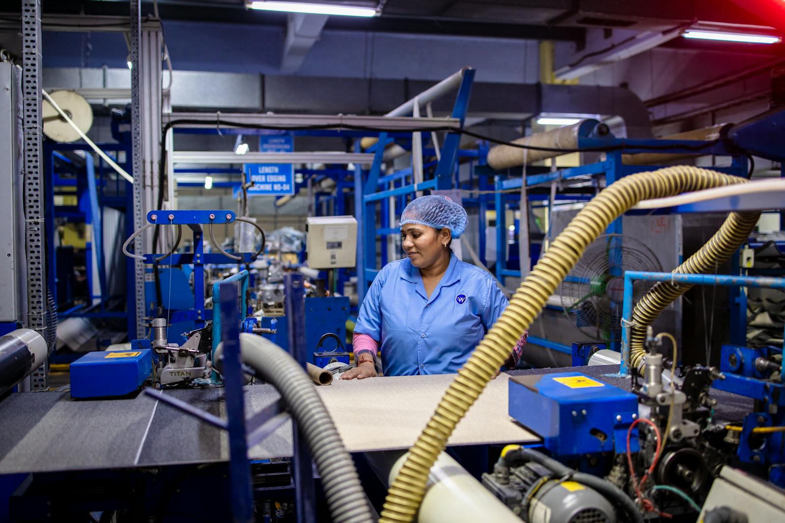 Indian female factory worker operating a converting machine, where base paper specified to IS 1397 becomes a finished carry bag