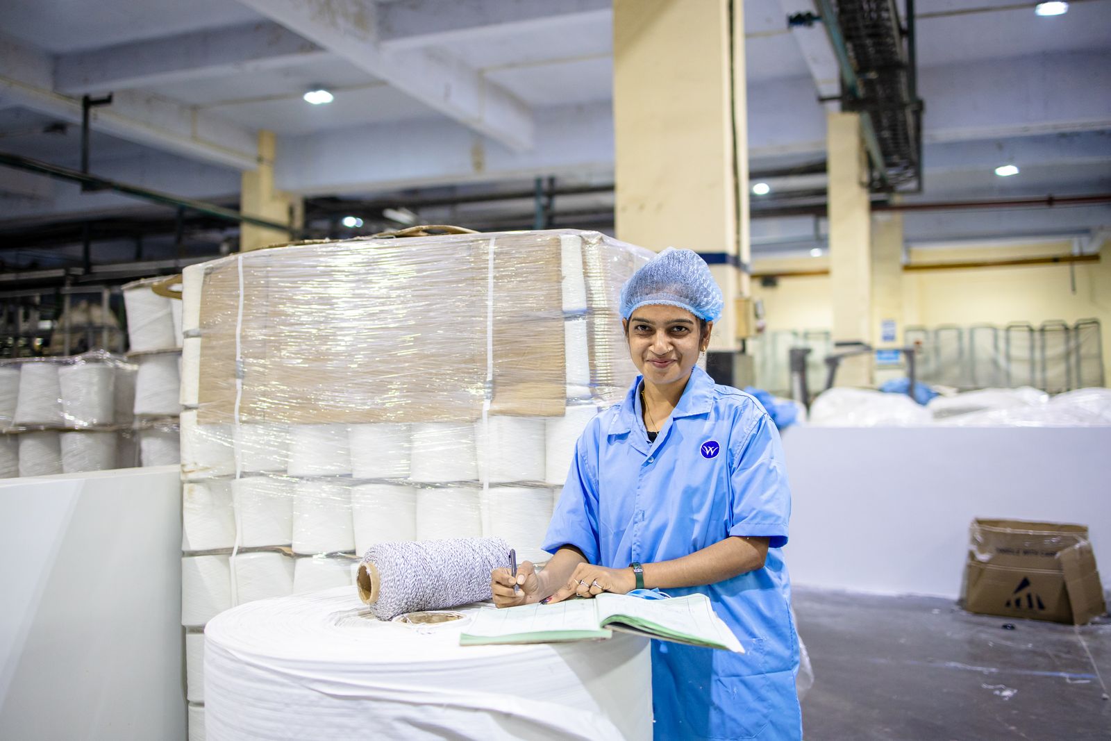 Indian factory worker logging notes beside production stock, the batch test data a QSR RFQ scorecard rewards