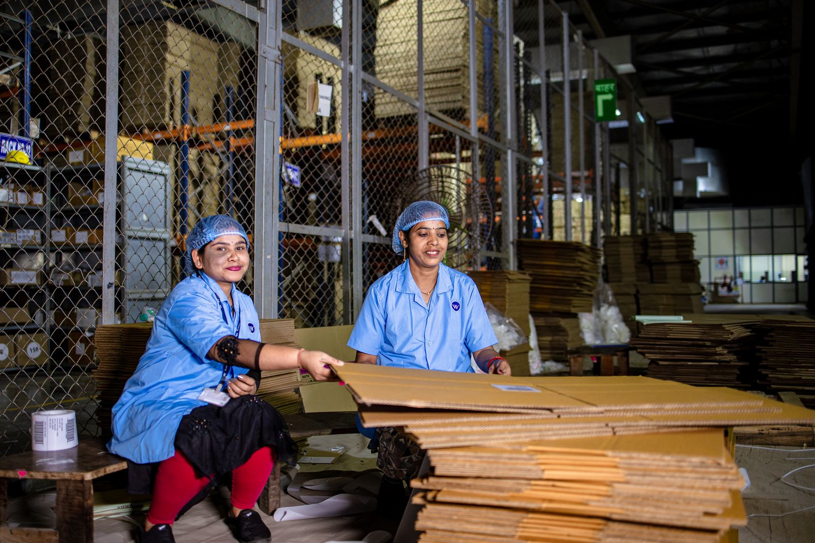 Two Indian workers in uniform handling cardboard in a warehouse, the supply capacity QSR procurement teams audit