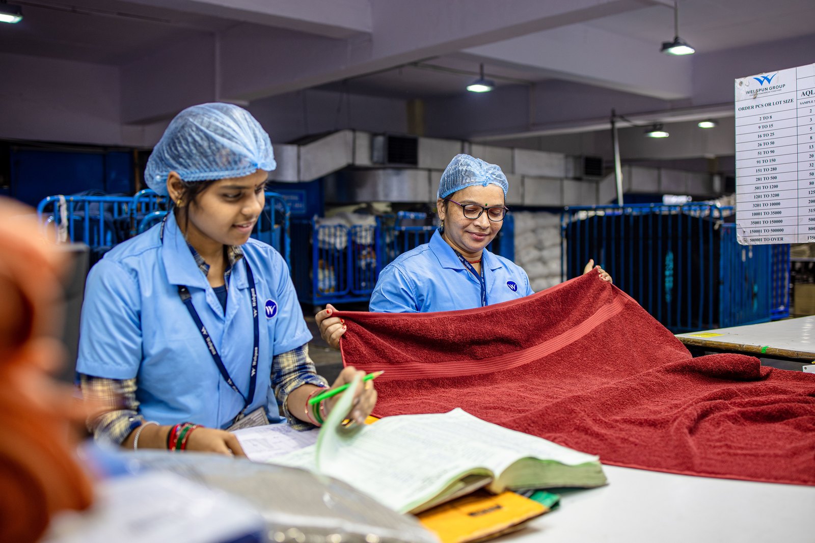 Two Indian factory workers inspecting material at a quality-control station to catch defects early