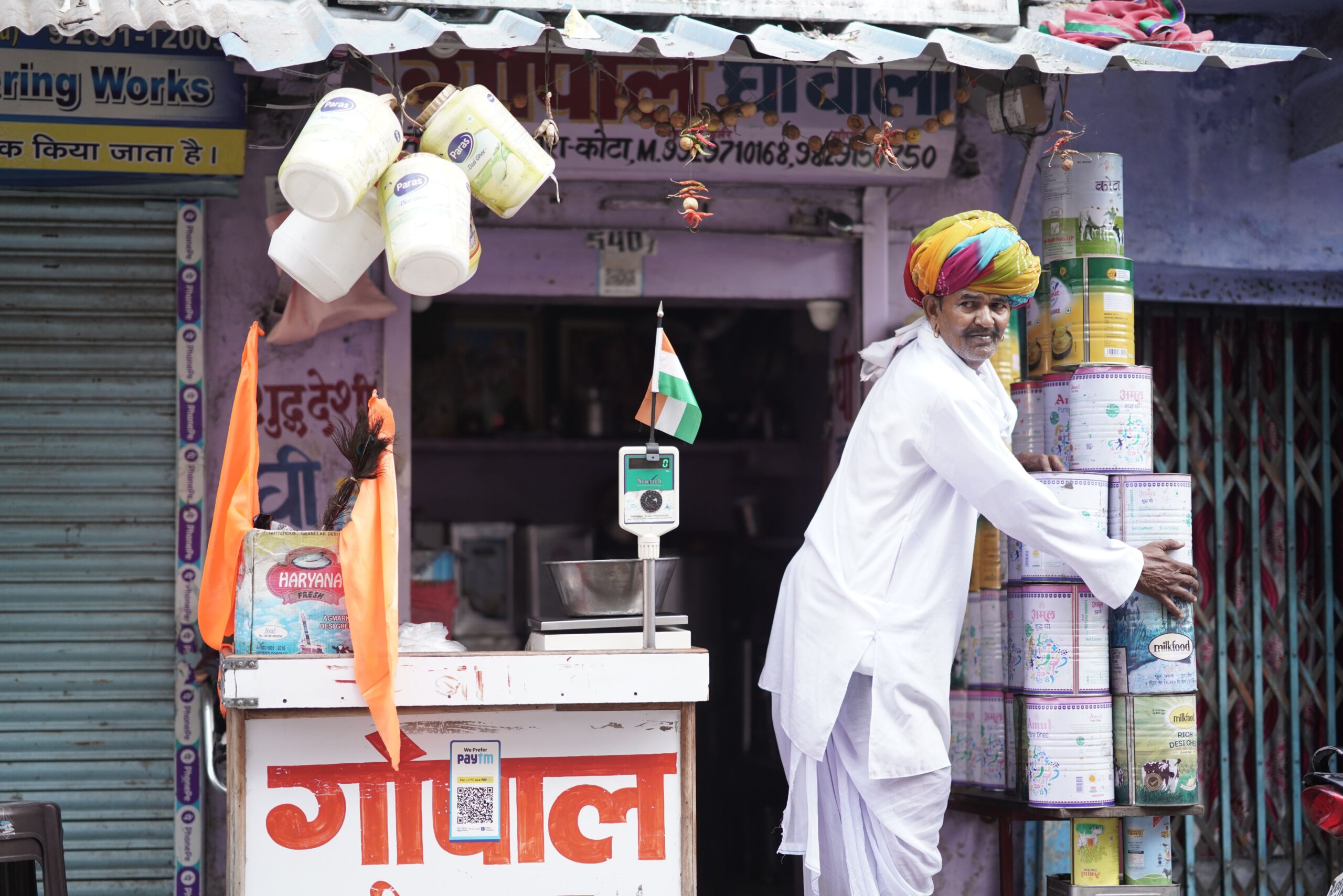 An Indian shopkeeper arranging packaged products outside a retail store
