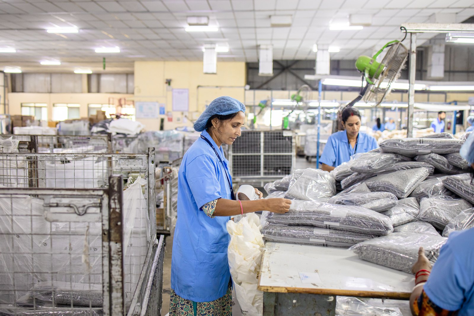 Indian factory workers sorting packaged materials by category, illustrating paper bag demand split across market segments