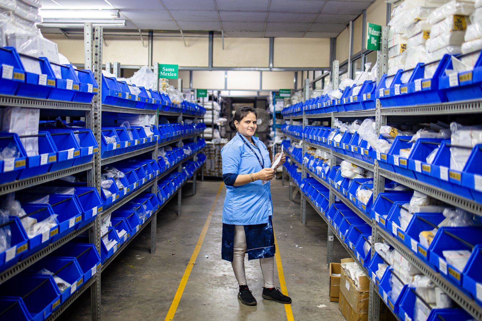 Indian warehouse worker organising reel and material inventory on racked shelving