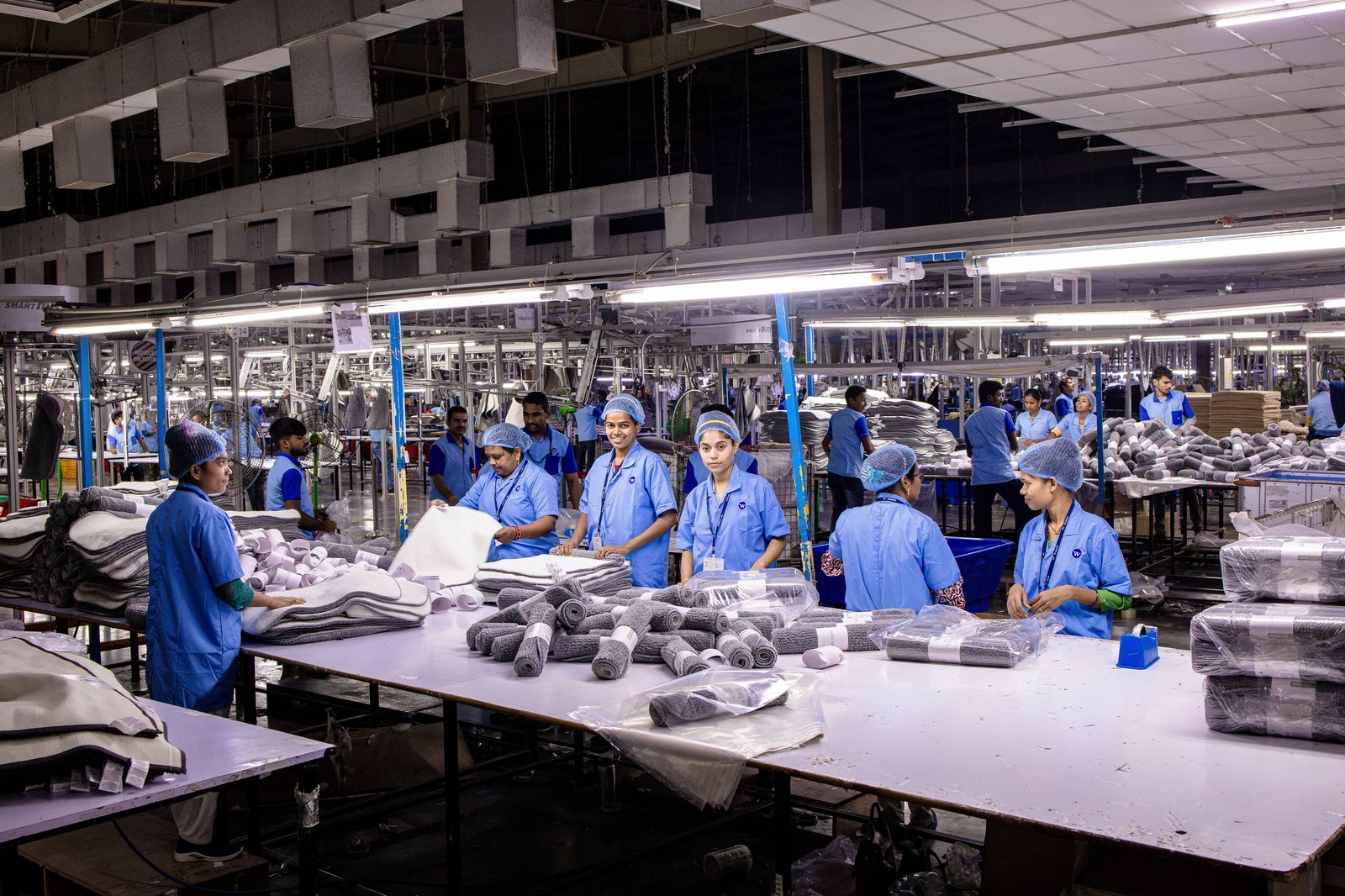Indian factory workers packaging finished products on an assembly line, representing printed paper bag production and quality output