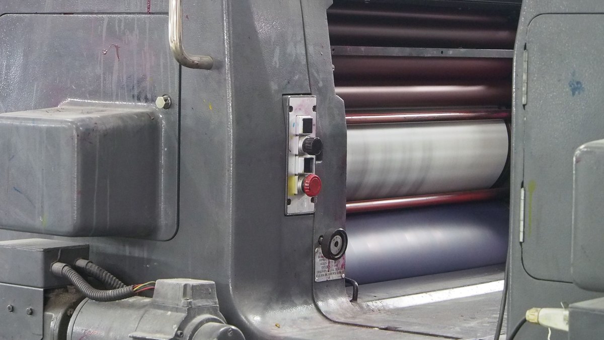 Close-up of industrial machine rollers in action, the coating nip that meters silicone coat weight onto a base paper