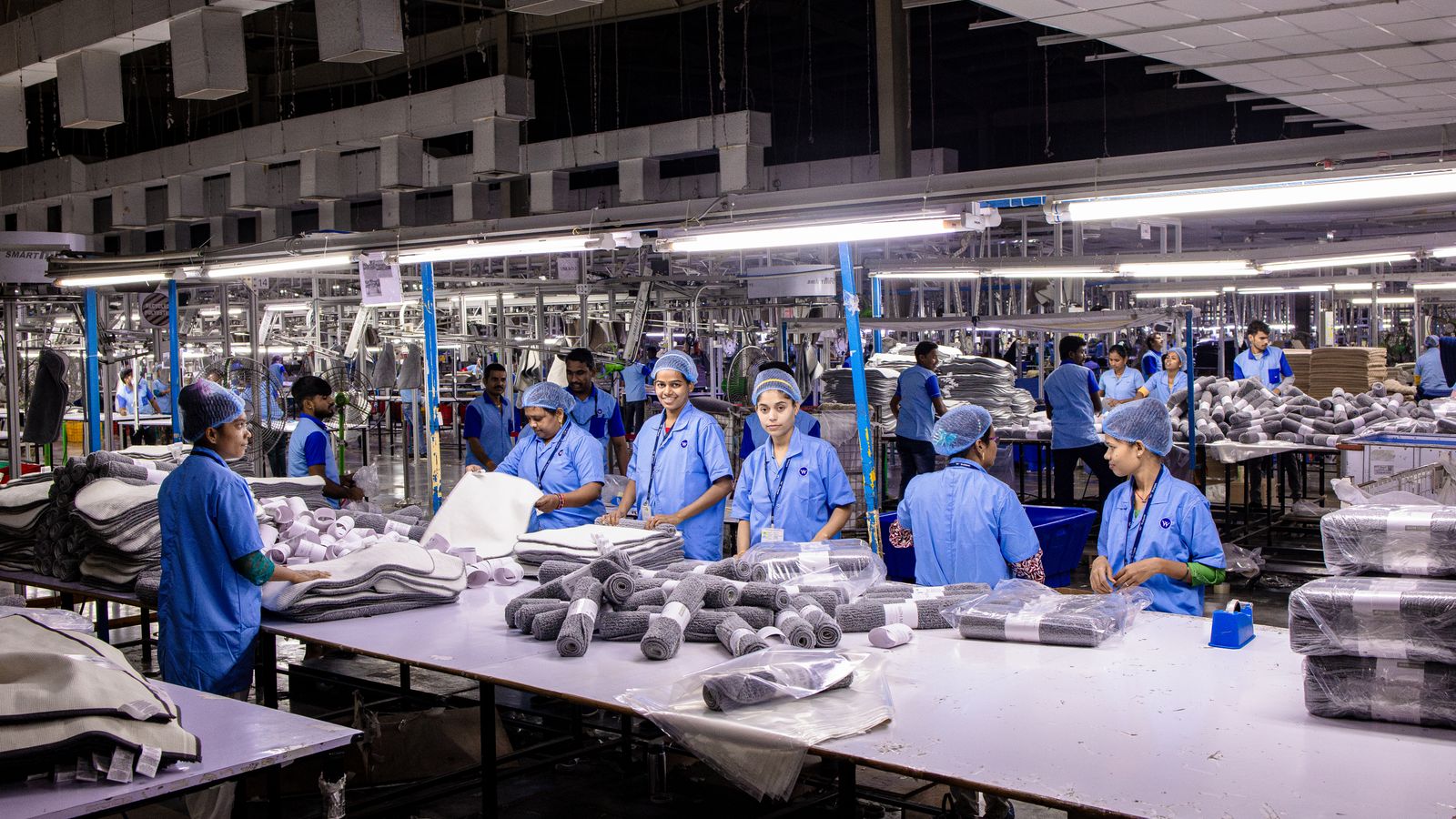 Indian factory workers packaging finished products on an assembly line