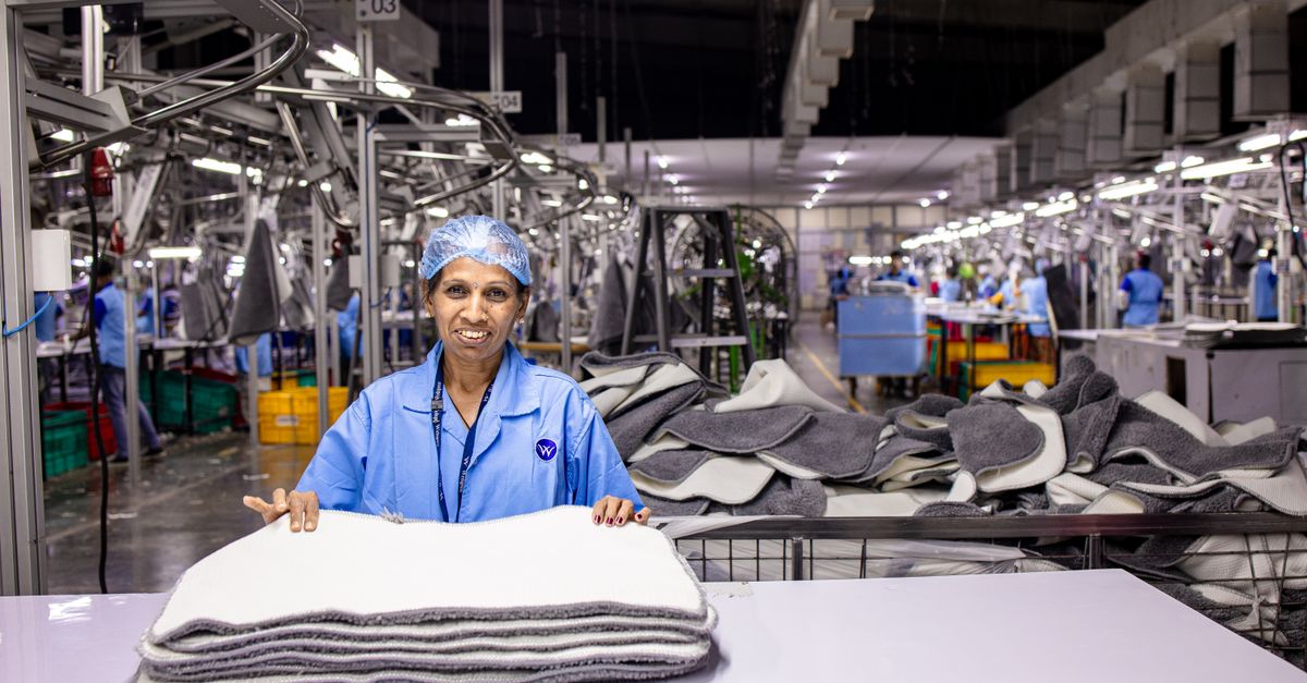Indian industrial worker handling material stacks in a manufacturing facility