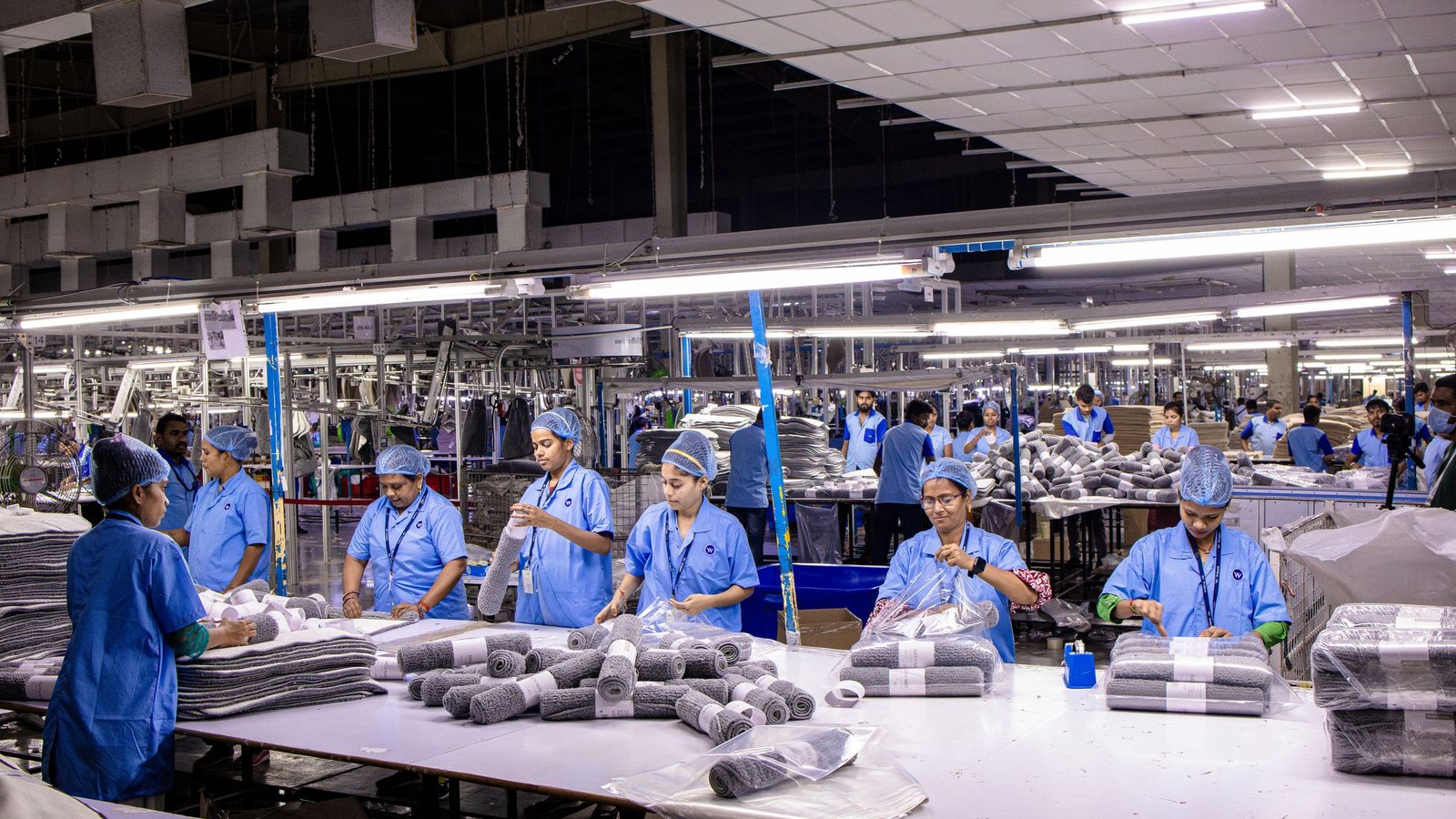 Workers handling material output in an Indian factory, comparable to reel handling and acceptance checks in a sachet converting plant