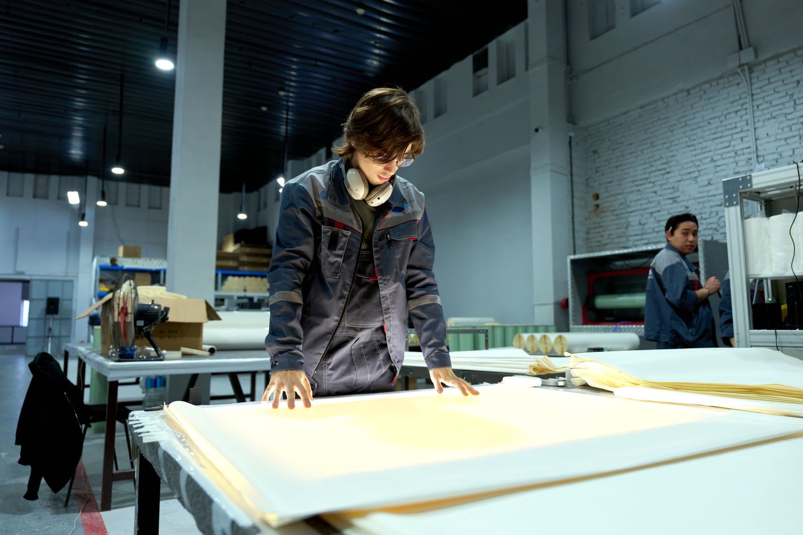 Worker inspecting sheet material for quality control in an industrial converting facility