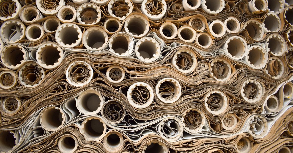End view of tightly stacked rolls of brown and white paper wound on cores, packed in wavy layers