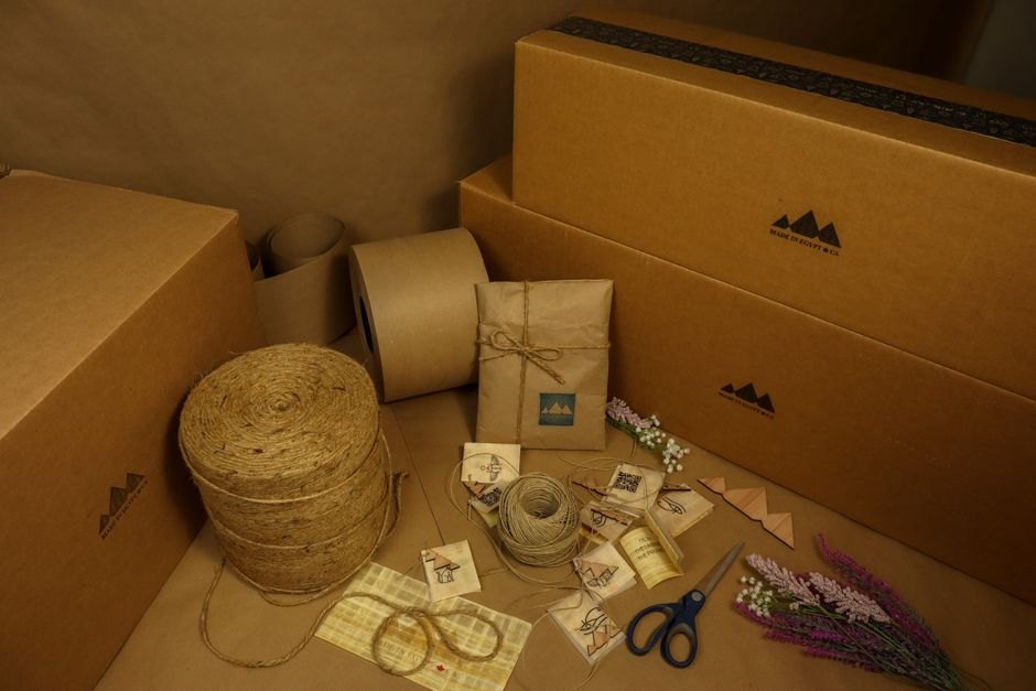 Brown kraft packaging materials laid flat including a paper roll, boxes and twine