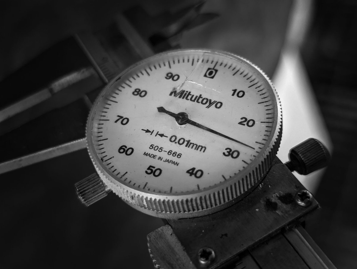 Close-up of a dial caliper gauge graduated in 0.01 mm divisions, black and white
